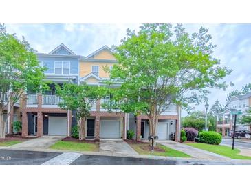 Townhome exterior featuring a brick facade, individual garages, and covered porches at 151 Braeside Ct, Cary, NC 27519