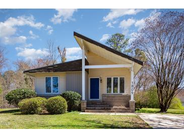 Charming single-story home featuring a unique roofline, blue front door, and lush landscaping at 1809 Coltrane Ct, Raleigh, NC 27610