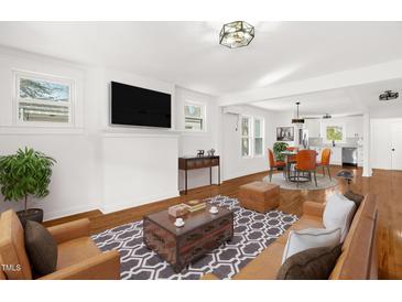 Open concept living room with hardwood floors, TV, stylish furniture and views to the kitchen at 507 Price Ave, Durham, NC 27701