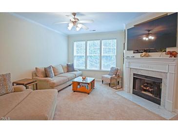 Cozy living room with fireplace, plush seating, and bright natural light from large windows at 5113 Lady Of The Lake Dr, Raleigh, NC 27612