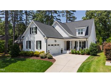 Charming white home with a black roof, lush landscaping, and an attached garage at 911 Canterbury Rd, Raleigh, NC 27607