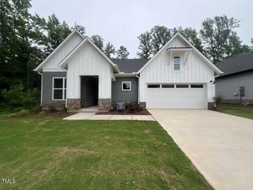 Charming home with white vertical siding, stone accents, a two-car garage, and a well-manicured lawn at 146 Wabash St, Pittsboro, NC 27312