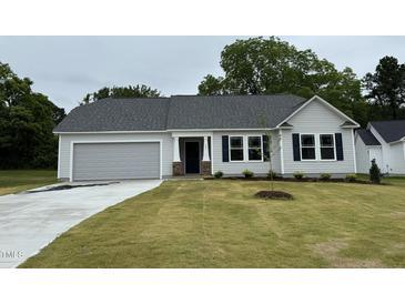 Charming single-story home with a gray exterior, manicured lawn, and attached garage offers modern curb appeal at 151 Oakfield Trace Dr, Four Oaks, NC 27524