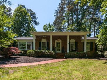 Charming brick home featuring a covered porch with white columns and a well-manicured front yard at 3421 Angus Rd, Durham, NC 27705