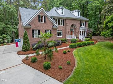 Beautiful brick home boasts manicured landscaping, healthy lawn, and a welcoming walkway to the front door at 5805 Laurel Rock Ln, Raleigh, NC 27613