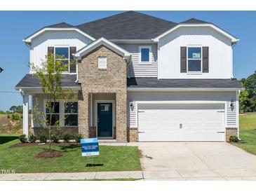 Charming two-story home with a brick facade, two-car garage, and well-manicured lawn at 667 White Birch Ln, Angier, NC 27501