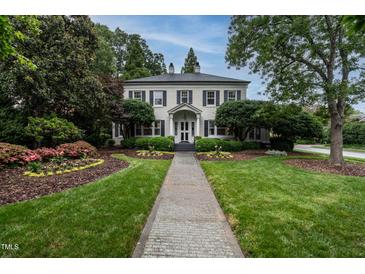 Stately white brick home with a manicured lawn, lush landscaping, and a charming brick walkway at 1002 Vance St, Raleigh, NC 27608