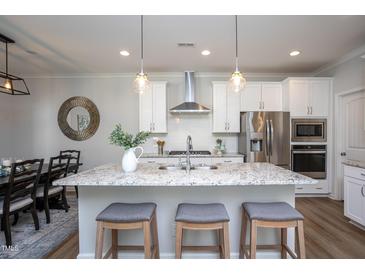 Bright kitchen features a granite island, stainless steel appliances, and white cabinets at 1048 Flagler St, Durham, NC 27713
