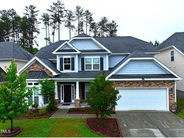 Beautiful two-story home featuring stone accents, a two-car garage, manicured lawn, and lush landscaping at 110 Elmsford St, Durham, NC 27707