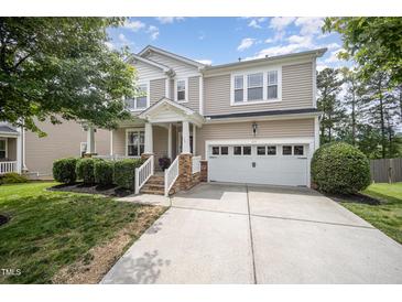 Charming two-story home with a manicured lawn, two-car garage, and covered front porch at 1211 Whispering Oak Ln, Durham, NC 27704