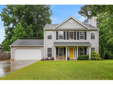 Charming two-story home with a well-manicured lawn, attached garage, and inviting yellow front door at 202 Stonecreek Dr, Apex, NC 27539