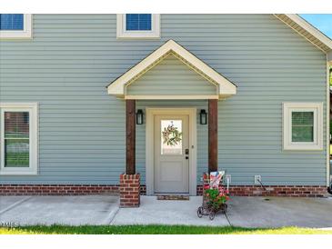 Inviting home entrance featuring a charming front door with a wreath and a decorative garden cart at 2258 Sanders Rd, Stem, NC 27581