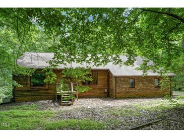 Charming home featuring wood and brick exterior, complemented by lush greenery, offering a serene and private setting at 4272 Boyd Wright Rd, Burlington, NC 27215