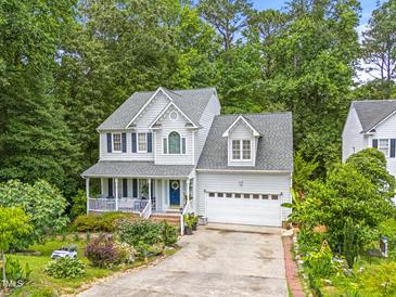Charming two-story home featuring a front porch, attached garage, and mature trees at 4705 Royal Troon Dr, Raleigh, NC 27604