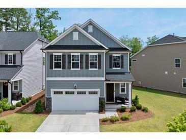 Charming two-story home featuring a gray exterior, manicured lawn, and a welcoming two-car garage at 6036 Balance Ct, Raleigh, NC 27616