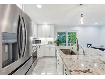 Bright kitchen featuring white cabinets, stainless steel appliances, and a large island with granite countertop at 6617 Whitted Rd, Fuquay Varina, NC 27526
