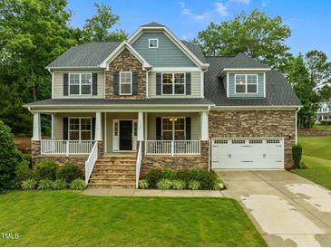 Charming two-story home with a welcoming front porch, manicured lawn, and attached two-car garage in a lovely community at 6949 Rex Rd, Holly Springs, NC 27540
