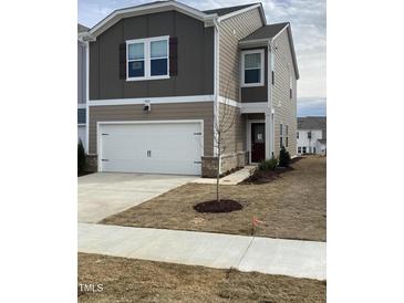 Inviting two-story home showcasing a well-maintained lawn, attached garage and neutral color palette at 909 Clearhaven Ln # 909, Fuquay Varina, NC 27526