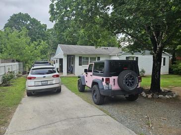 Charming single-story home with white painted brick, a driveway, and mature shade trees in a residential neighborhood at 118 Lynn Rd, Durham, NC 27703