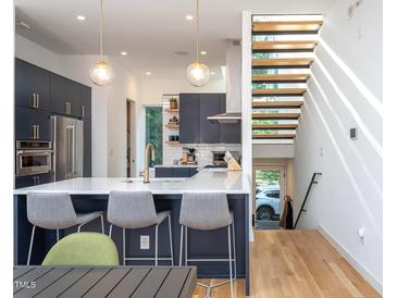 Bright, modern kitchen with a waterfall island, stainless steel appliances, and stylish pendant lighting at 414 Chavis Way, Raleigh, NC 27601