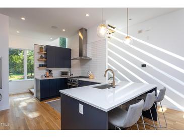 Bright, modern kitchen with stainless steel appliances, quartz countertops, and a spacious island with barstool seating at 414 Chavis Way, Raleigh, NC 27601