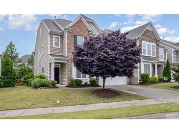 Charming two-story home with a combination of brick and siding, complemented by a beautifully landscaped front yard and a mature tree at 522 Finnbar Dr, Cary, NC 27519