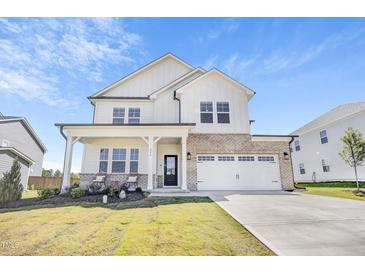 Beautiful two-story home with a brick and white siding, a two-car garage, and a well-manicured lawn at 604 Salmonberry Dr, Holly Springs, NC 27540