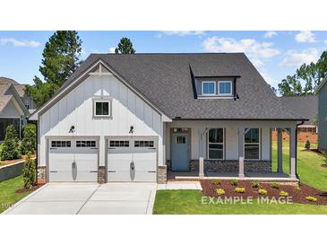 Charming home with a two-car garage, inviting front porch, and lovely blue front door at 112 Cultivator Ct, Angier, NC 27501