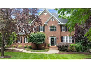 Stately brick home featuring a well-manicured lawn and mature landscaping at 1332 Kinsdale Dr, Raleigh, NC 27615