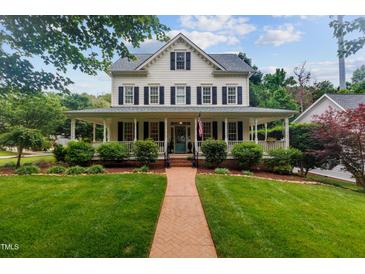 Charming home featuring a spacious front porch, manicured lawn and beautiful brick walkway at 200 Cobblepoint Way, Holly Springs, NC 27540