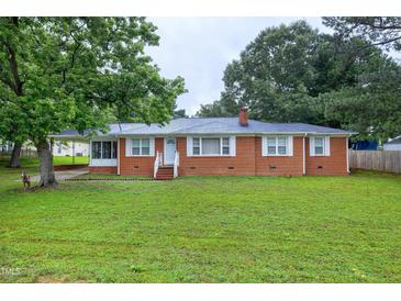 Charming brick home with a well-manicured lawn, lush trees and inviting front porch at 2016 Tryon Rd, Raleigh, NC 27603