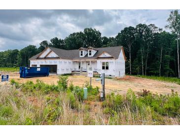 New construction home featuring Tyvek wrap, dormers, attached garage, and partially cleared lot ready for finishing touches at 204 Seahawk Way, Zebulon, NC 27597