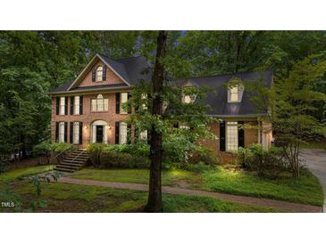 Two-story brick home with a welcoming front porch, black shutters, and professional landscaping at 220 Dalton Dr, Raleigh, NC 27615