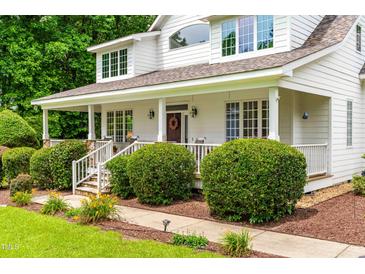 Inviting front porch with white columns, beautiful landscaping, and charming details at 228 Birch Creek Dr, Fuquay Varina, NC 27526