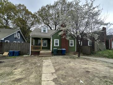Charming green home featuring a cozy front porch, flowering trees, and a brick chimney at 2505 Chapel Hill Rd, Durham, NC 27707