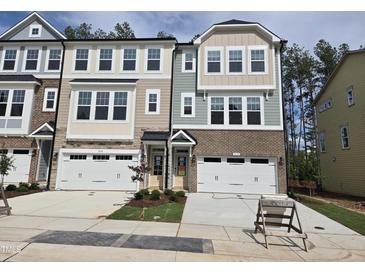 Charming townhome exterior features brick accents, white garage doors and manicured landscaping at 5028 Jowetts Walk Dr # 24, Cary, NC 27519