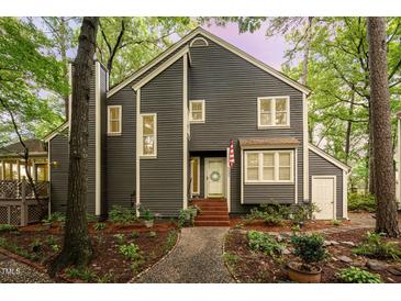 Charming two-story home with gray siding, white trim, and a welcoming front porch surrounded by mature trees at 6035 Sentinel Dr, Raleigh, NC 27609