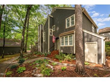 Charming two-story home with landscaped yard and gray siding, nestled in a wooded area at 6035 Sentinel Dr, Raleigh, NC 27609