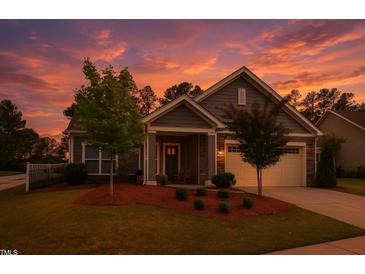 Charming home featuring manicured landscaping, a two-car garage, and a cozy front porch at sunset at 1357 Prevenient Dr, Wake Forest, NC 27587