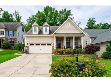 Charming home featuring a two-car garage, front porch, and well-manicured landscaping at 1577 Tice Hurst Ln, Apex, NC 27502
