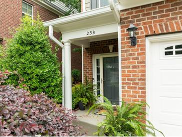 Inviting brick entryway with black front door, white trim, and mature landscaping at 238 Langford Valley Way, Cary, NC 27513