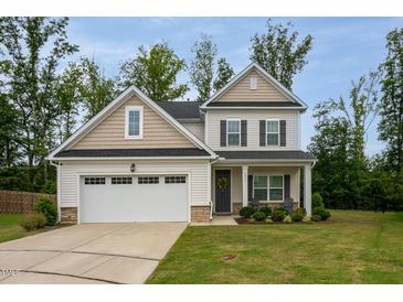 Charming two-story home with a well-manicured lawn, attached garage, and inviting front porch at 2521 Heathland Farm Dr, Fuquay Varina, NC 27526
