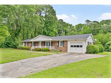 Charming brick ranch home with well-manicured lawn, covered porch, and attached garage on a tree-lined street at 3114 Alabama Ave, Durham, NC 27705