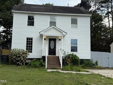 Two-story home with white siding, a black front door, chimney, and mature landscaping at 3825 Old Coach Rd, Raleigh, NC 27616