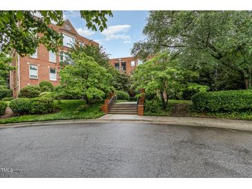 Brick condo building featuring manicured lawns, mature landscaping, and a welcoming walkway at 620 Martin Luther King Jr. Blvd # 302, Chapel Hill, NC 27514