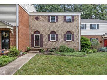 Charming brick townhome featuring a manicured lawn and shuttered windows at 6423 New Market Way, Raleigh, NC 27615