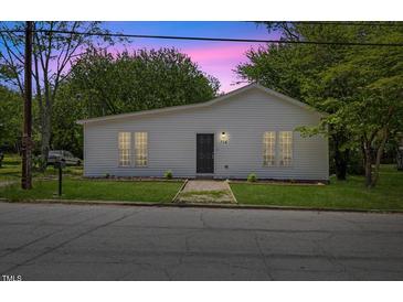 Charming one-story home with white siding, a dark front door, and a well-manicured front lawn at 714 Harriett St, Henderson, NC 27536
