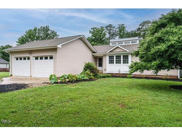 Charming single-story home featuring a well-manicured lawn, front garden, and a two-car garage at 8204 Charlbert Ct, Apex, NC 27539