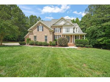 Beautiful brick home with manicured lawn, mature trees, and a welcoming front porch at 85 Pebble Creek Dr, Franklinton, NC 27525