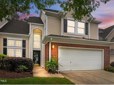 Charming home with a two-car garage, brick accents, and manicured landscaping under a colorful twilight sky at 103 Lake Tillery Dr, Cary, NC 27519